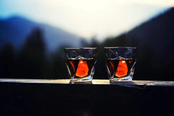 Chupito de whisky al atardecer cielo dramático en bac paisaje de montaña — Foto de Stock