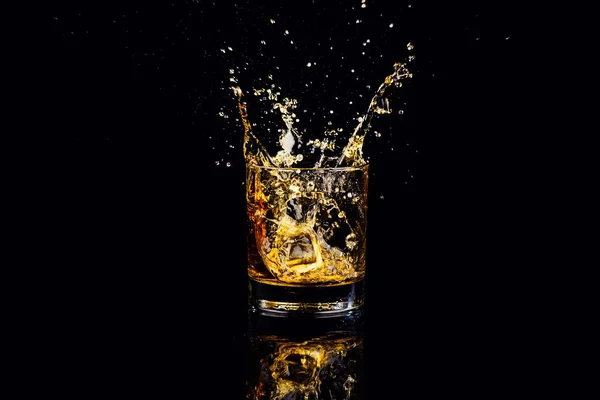 Geïsoleerde shot whisky met splash op zwarte achtergrond — Stockfoto