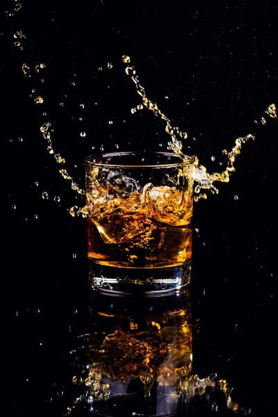 Isolerad bild av whisky med stänk på svart bakgrund — Stockfoto