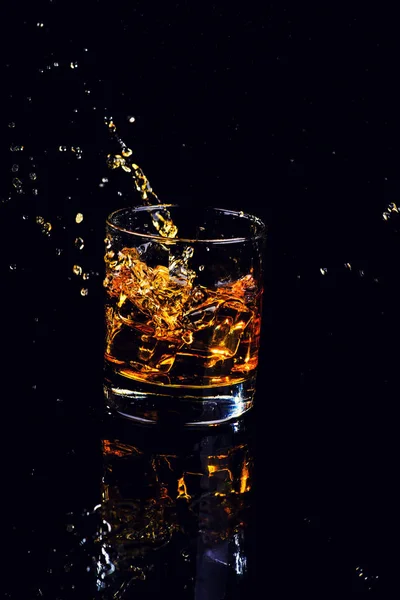 黒の背景にスプラッシュとウイスキーの孤立ショット — ストック写真