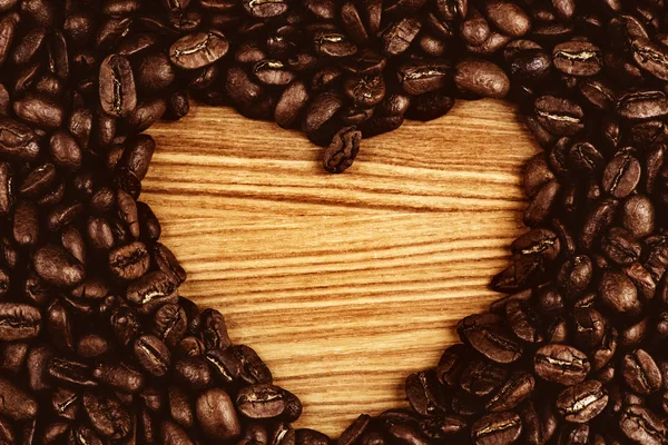 Heart shape made from coffee beans on wooden surface — Stock Photo, Image