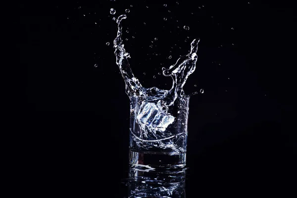 Geïsoleerd koud water in een glas met plons en ijsblokjes op b — Stockfoto