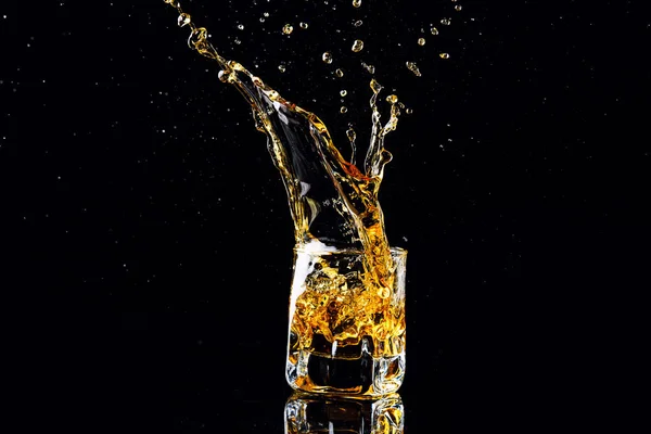 Isolated shot of whiskey with splash on black background, brandy — Stock Photo, Image