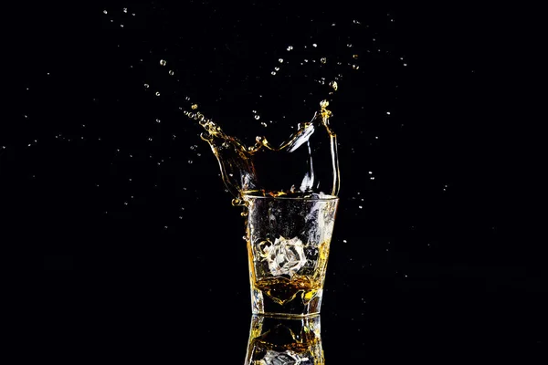 Isolerade skott av whisky med stänk på svart bakgrund, konjak — Stockfoto