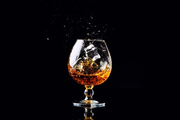 Glas met cognac op een zwarte achtergrond — Stockfoto