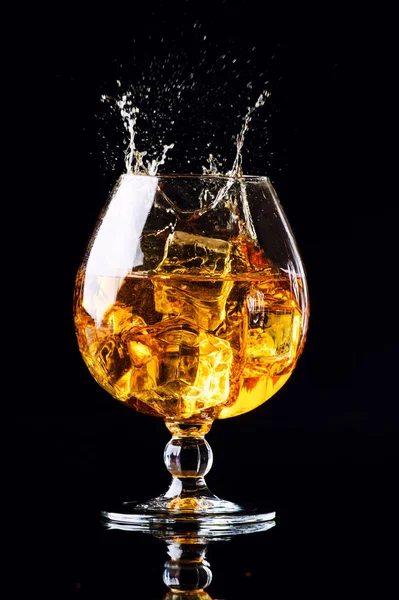 Glas met cognac op een zwarte achtergrond — Stockfoto