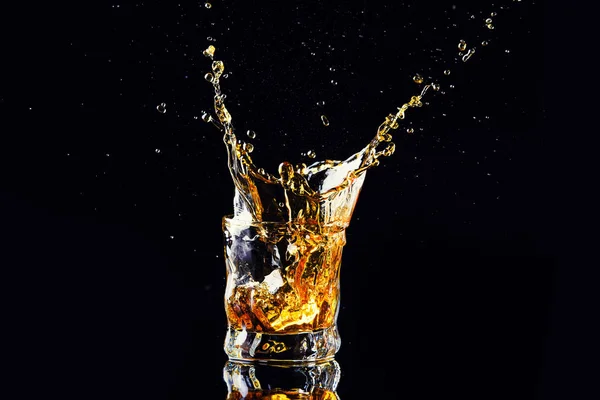 Colpo isolato di whisky con spruzzata su fondo nero, brandy — Foto Stock