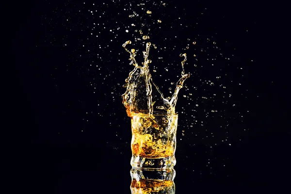 Strzał na białym tle whisky z splash na czarnym tle, brandy — Zdjęcie stockowe