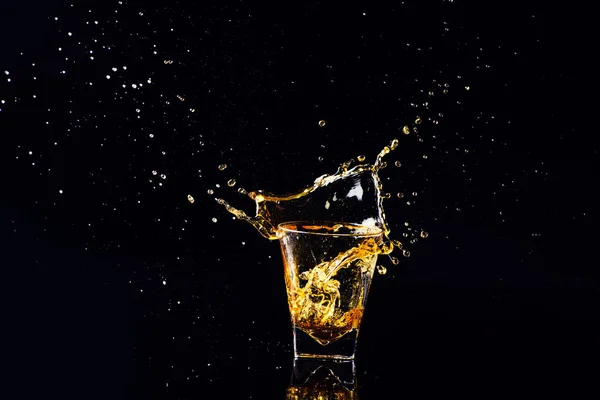 Tiro aislado de whisky con salpicadura sobre fondo negro, brandy —  Fotos de Stock
