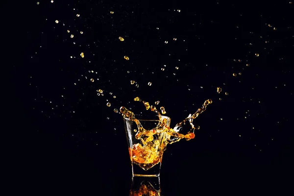 Tiro aislado de whisky con salpicadura sobre fondo negro, brandy — Foto de Stock
