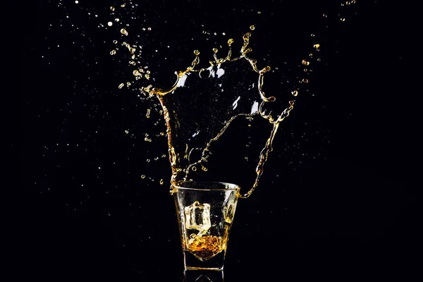 Изолированный выстрел виски с брызгами на черном фоне, бренди — стоковое фото