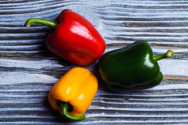 Set of three peppers on wooden background. Yellow, red and green