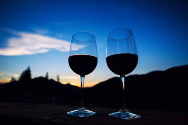 İki bardak şarap günbatımı dramatik gökyüzü üzerinde dağ manzarası