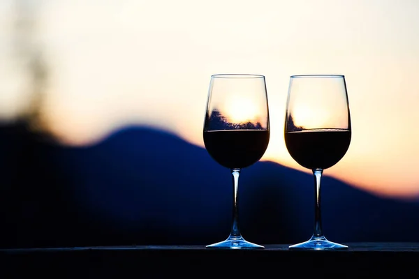 Due bicchieri di vino al tramonto cielo drammatico sul paesaggio montano — Foto Stock