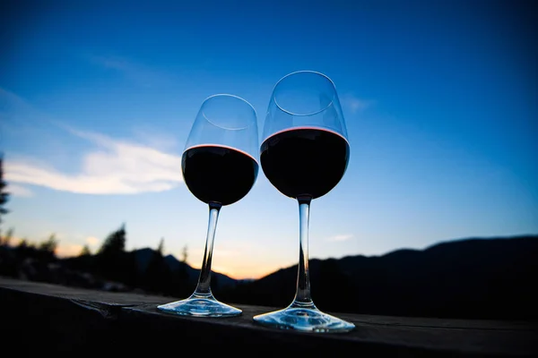 Due bicchieri di vino al tramonto cielo drammatico sul paesaggio montano — Foto Stock