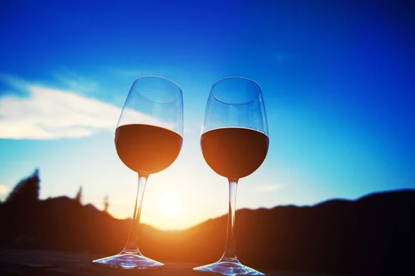 Due bicchieri di vino al tramonto cielo drammatico sul paesaggio montano — Foto Stock