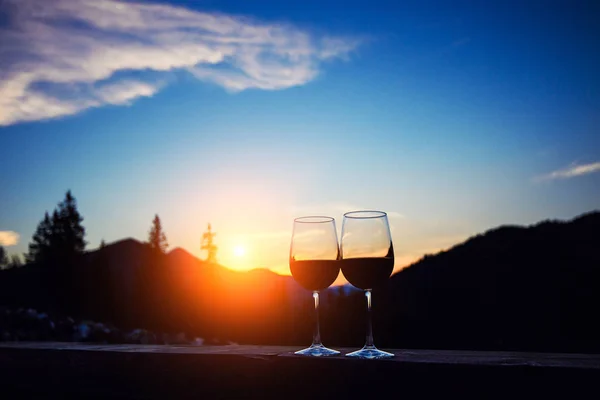 Due bicchieri di vino al tramonto cielo drammatico sul paesaggio montano — Foto Stock