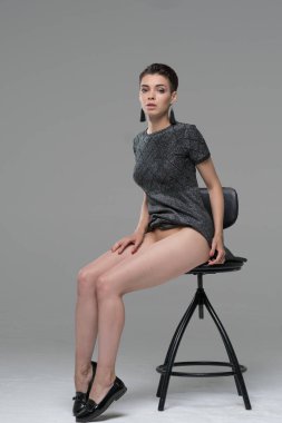 Genç güzel kız Giydir sandalye üzerinde oturan Studio'da poz