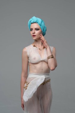 Genç güzel kız stüdyoda ayakta beyaz şeffaf giysiler içinde poz