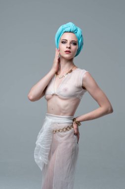 Genç güzel kız stüdyoda ayakta beyaz şeffaf giysiler içinde poz