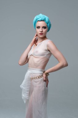 Genç güzel kız stüdyoda ayakta beyaz şeffaf giysiler içinde poz