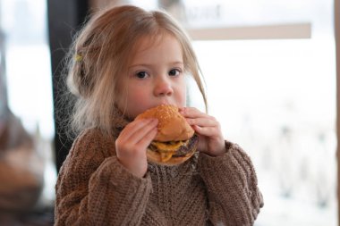 küçük kız kafede hamburger yemek