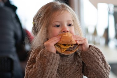 küçük kız kafede hamburger yemek