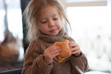 küçük kız kafede hamburger yemek