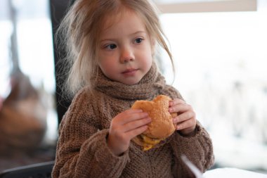 küçük kız kafede hamburger yemek