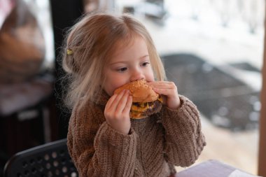 küçük kız kafede hamburger yemek