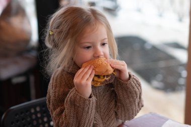 küçük kız kafede hamburger yemek