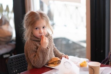 küçük kız kafede hamburger yemek