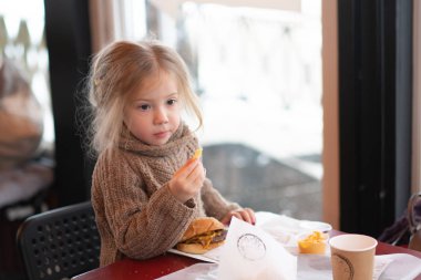 küçük kız kafede hamburger yemek