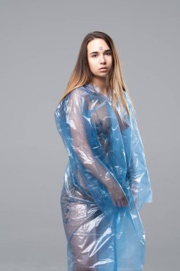 Genç güzel kız stüdyoda bir mavi yağmurluk ayakta poz