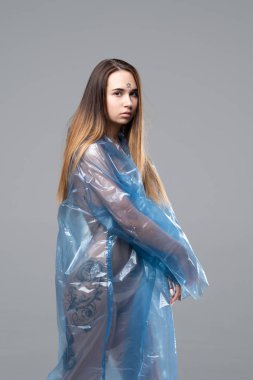 Genç güzel kız stüdyoda bir mavi yağmurluk ayakta poz