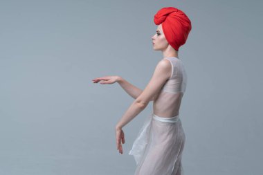 Genç güzel kız stüdyoda ayakta beyaz şeffaf giysiler içinde poz