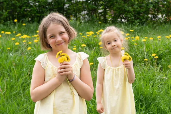 Two Girls Green Grass Dandelions Standing Yellow Dresses — Stock Photo, Image