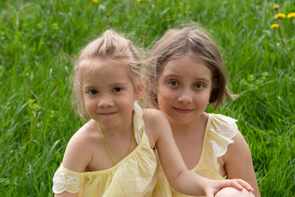 Two Girls Sit Green Grass Yellow Dresses — Stock Photo, Image