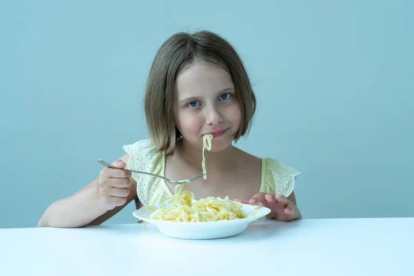 Μικρό Κορίτσι Τρώγοντας Ζυμαρικά Κάθεται Ένα Τραπέζι Ένα Κίτρινο Φόρεμα — Φωτογραφία Αρχείου