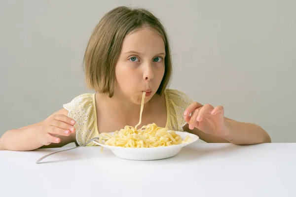 小女孩在白色的餐桌上吃意大利面 — 图库照片