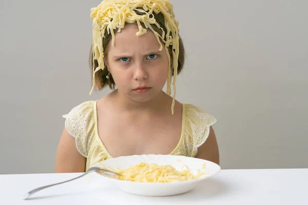 白いテーブルでパスタを食べる小さな女の子 — ストック写真