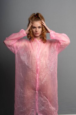 genç güzel kız stüdyoda poz, pembe bir yağmurluk ayakta