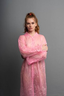 genç güzel kız stüdyoda poz, pembe bir yağmurluk ayakta
