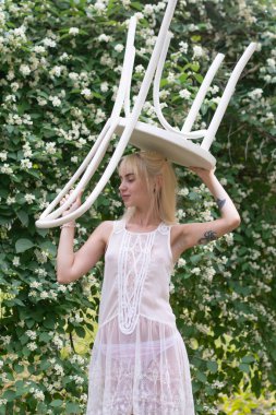 Genç güzel kız dışarıda poz veriyor, leylak çalılarının yanında duruyor.