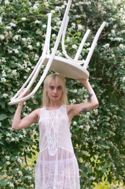 Genç güzel kız dışarıda poz veriyor, leylak çalılarının yanında duruyor.