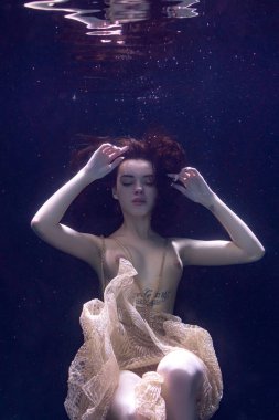 genç güzel kız çıplak sualtı poz, altın bir elbise içinde bir havuzda yüzme