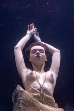 genç güzel kız çıplak sualtı poz, altın bir elbise içinde bir havuzda yüzme