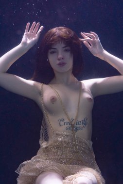 genç güzel kız çıplak sualtı poz, altın bir elbise içinde bir havuzda yüzme