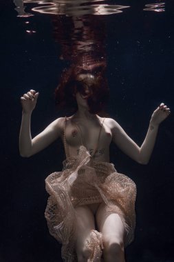 genç güzel kız üstsüz bir elbise içinde sualtı yüzer