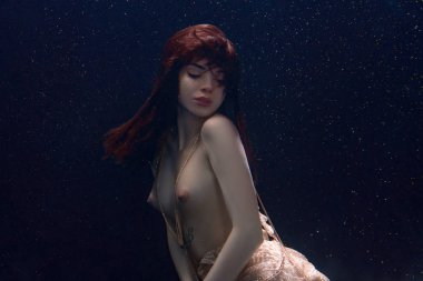 genç güzel kız üstsüz bir elbise içinde sualtı yüzer